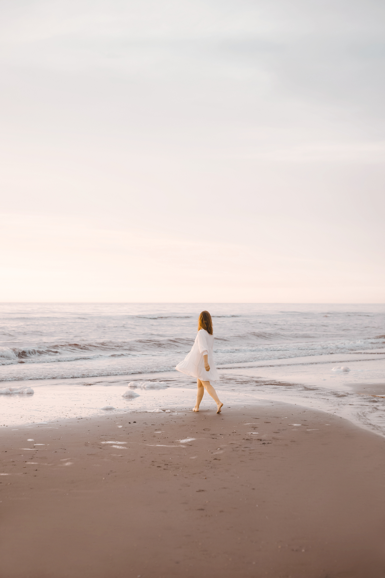 Vrouw wandelt op het strand bij zonsondergang
